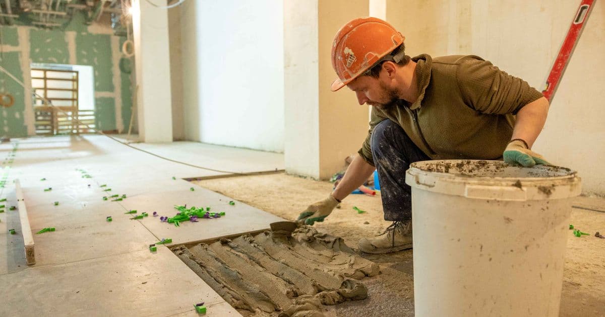 Bauarbeiter verlegt Bodenplatten auf einer Baustelle während einer Renovation