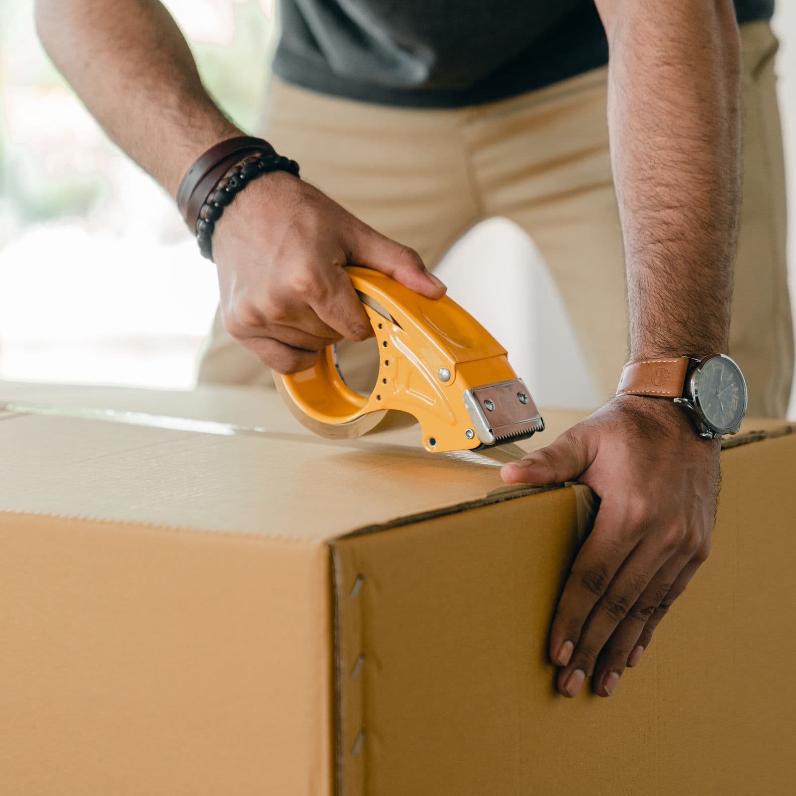 Mitarbeiter einer Umzugsfirma verpackt einen Umzugskarton mit Klebeband