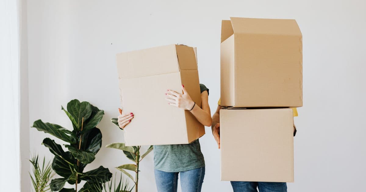 Zwei Personen tragen Umzugskartons in eine Wohnung