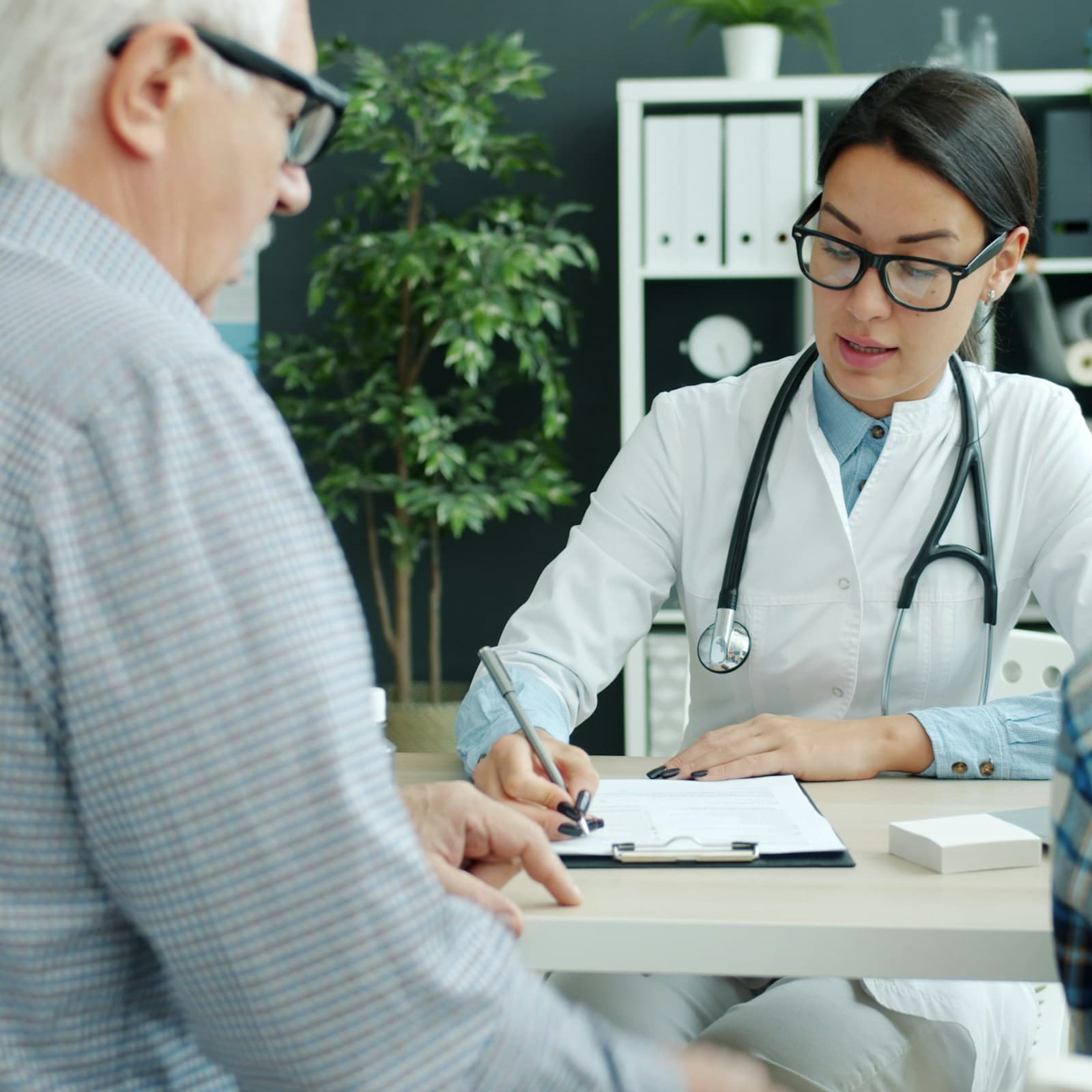 Ärztin im Gespräch mit einem älteren Patienten in einer Schweizer Hausarztpraxis